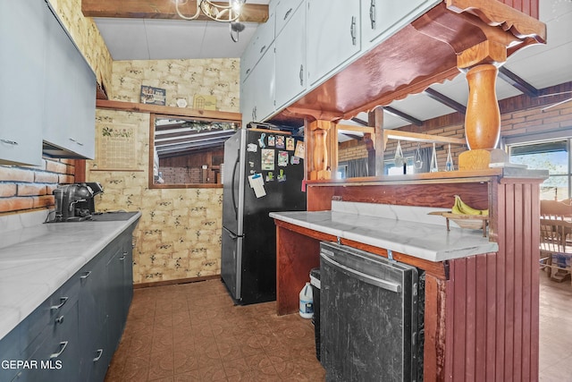 kitchen with white cabinets, vaulted ceiling with beams, stainless steel fridge, and brick wall