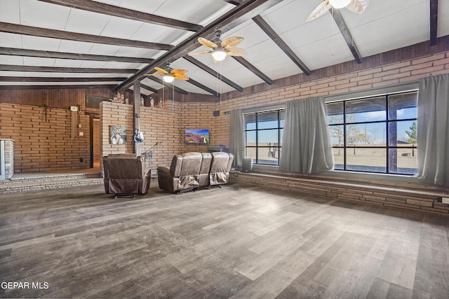 unfurnished living room with hardwood / wood-style flooring, ceiling fan, lofted ceiling with beams, and brick wall