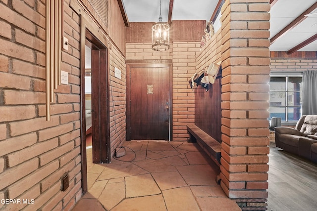 entryway featuring beam ceiling and brick wall