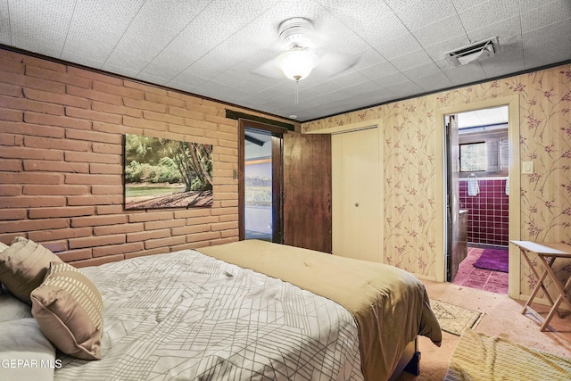 bedroom with ceiling fan, a closet, and brick wall