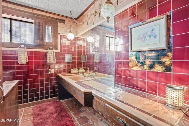 bathroom featuring a textured ceiling, a healthy amount of sunlight, and tile walls