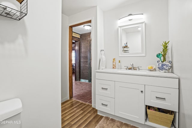 bathroom with hardwood / wood-style flooring, vanity, and toilet