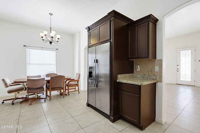 kitchen with dark brown cabinetry, light stone countertops, stainless steel refrigerator with ice dispenser, and light tile patterned floors