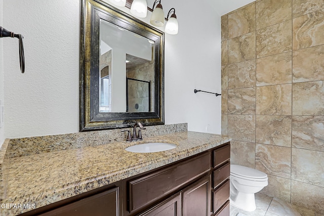 bathroom featuring toilet, vanity, tile patterned floors, and walk in shower