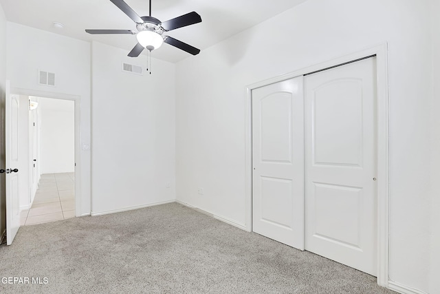 unfurnished bedroom featuring light carpet, a closet, and ceiling fan