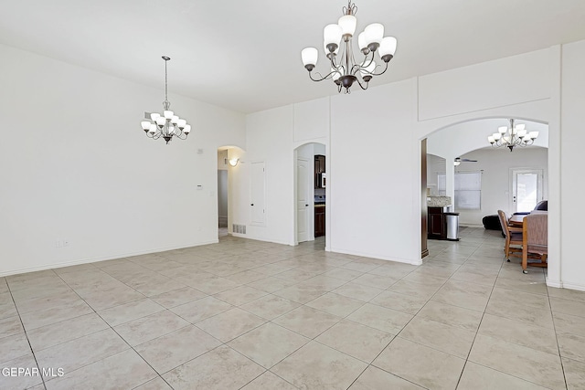 empty room with light tile patterned flooring and ceiling fan with notable chandelier