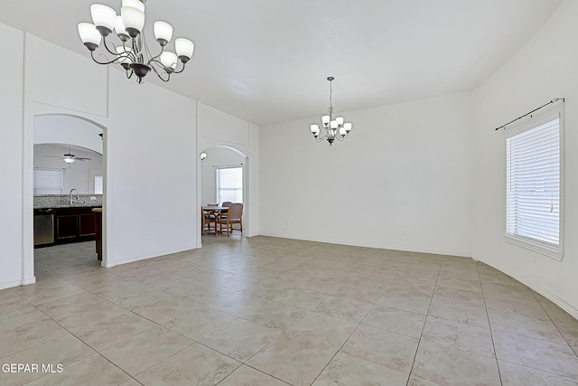 tiled empty room featuring ceiling fan with notable chandelier and sink