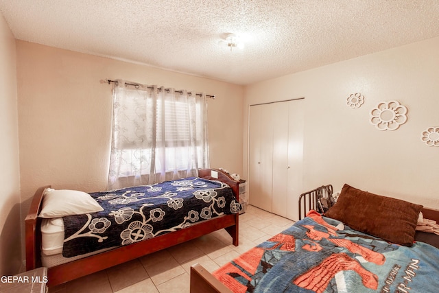 tiled bedroom featuring a textured ceiling and a closet