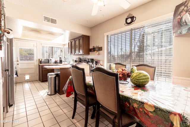 dining area featuring ceiling fan, light tile patterned floors, and a textured ceiling