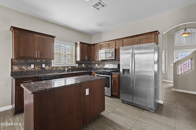 kitchen with decorative backsplash, a center island, stainless steel appliances, and sink