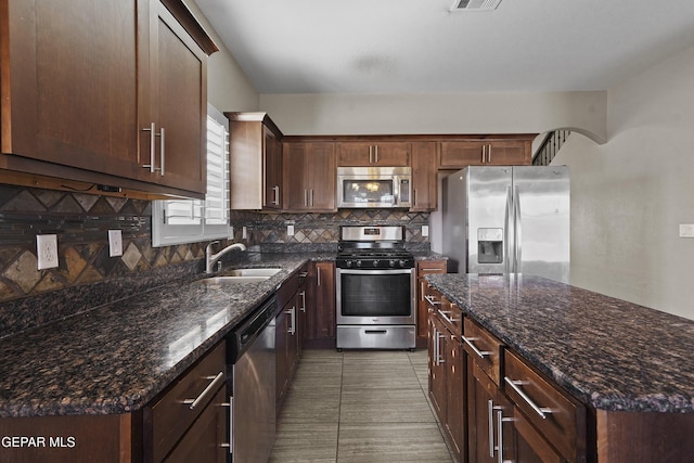 kitchen featuring dark stone counters, sink, decorative backsplash, appliances with stainless steel finishes, and light tile patterned flooring