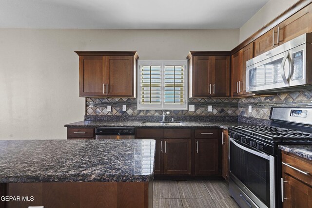 kitchen with tasteful backsplash, sink, dark stone counters, and appliances with stainless steel finishes