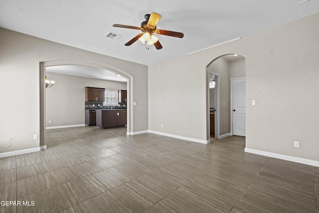 unfurnished living room featuring ceiling fan with notable chandelier