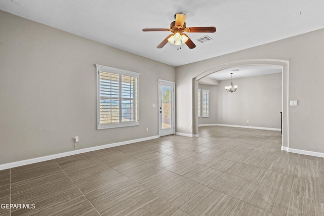 spare room featuring ceiling fan with notable chandelier