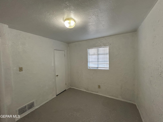 unfurnished room featuring a textured ceiling and concrete floors