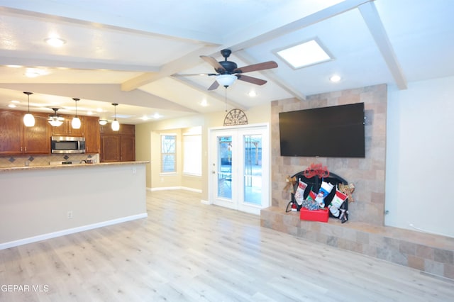 unfurnished living room featuring ceiling fan, vaulted ceiling with beams, and light wood-type flooring