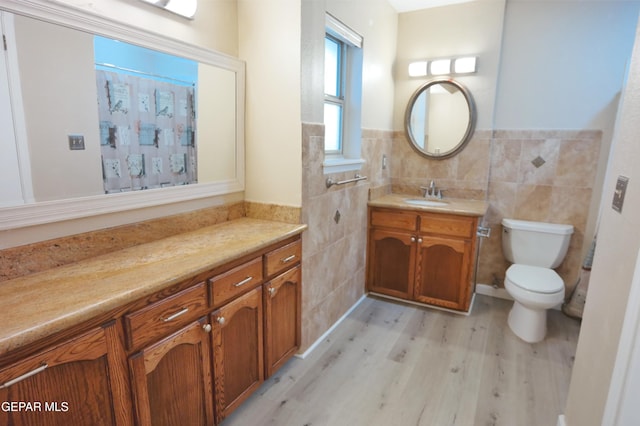 bathroom with toilet, tile walls, hardwood / wood-style flooring, and vanity