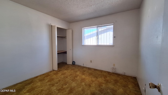 unfurnished bedroom featuring carpet, a textured ceiling, and a closet