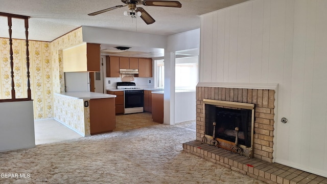 kitchen with ceiling fan, a brick fireplace, light colored carpet, wooden walls, and white stove