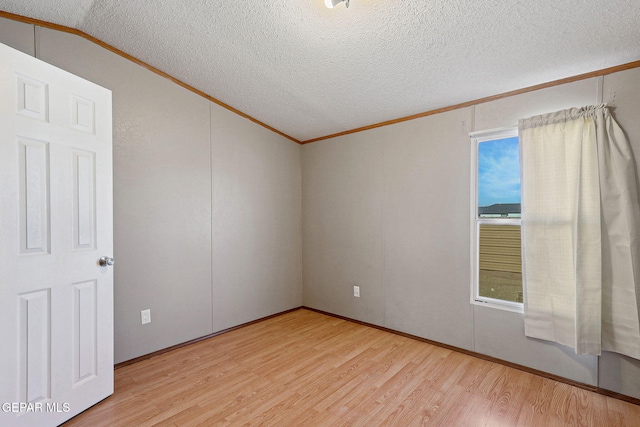 empty room featuring lofted ceiling, light hardwood / wood-style floors, and crown molding