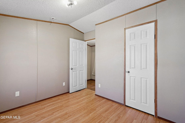 unfurnished bedroom featuring a textured ceiling, light wood-type flooring, crown molding, and lofted ceiling