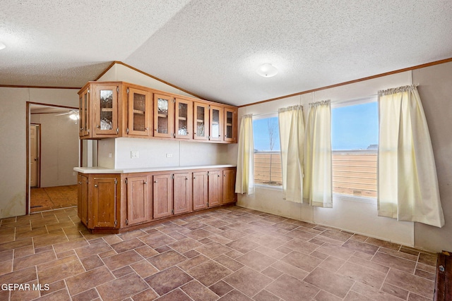 kitchen with plenty of natural light, lofted ceiling, kitchen peninsula, and ornamental molding