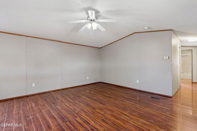 empty room with ceiling fan, hardwood / wood-style floors, lofted ceiling, a textured ceiling, and ornamental molding