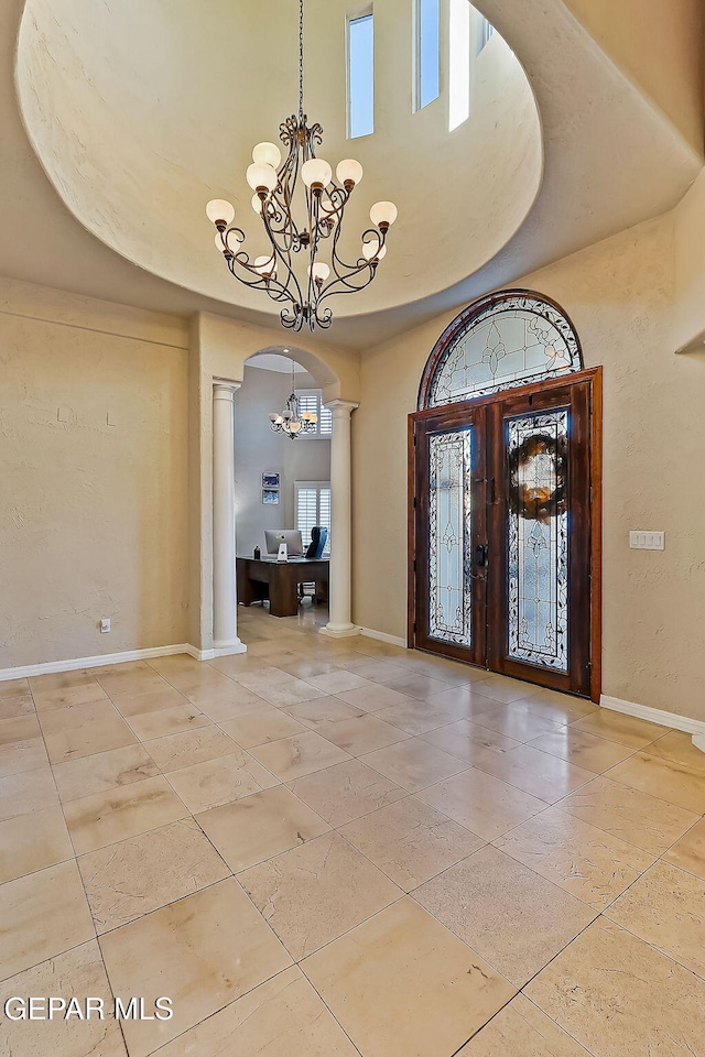 foyer featuring ornate columns, a high ceiling, and french doors