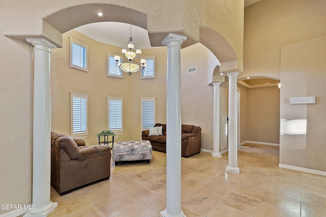 living room with a towering ceiling, ornamental molding, and a chandelier