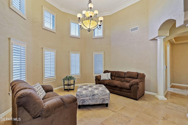 tiled living room with a notable chandelier, plenty of natural light, ornate columns, and crown molding