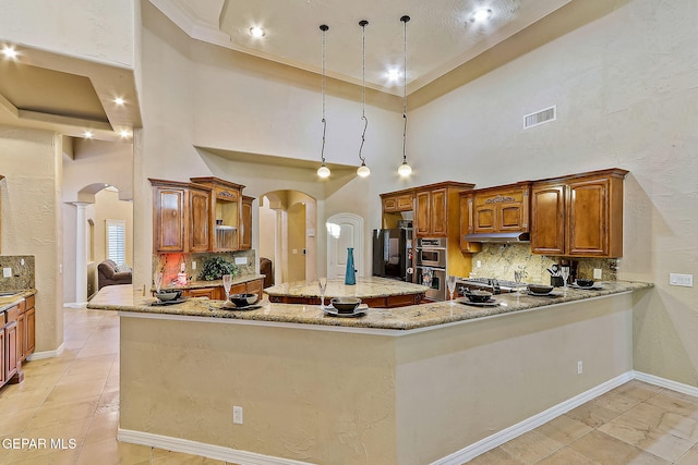 kitchen with a high ceiling, tasteful backsplash, black fridge, kitchen peninsula, and pendant lighting