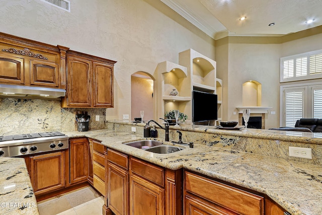 kitchen featuring light stone countertops, tasteful backsplash, stainless steel gas cooktop, sink, and light tile patterned floors