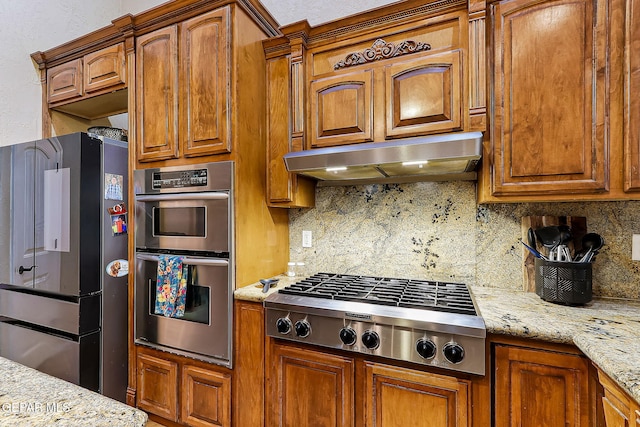 kitchen featuring light stone countertops, appliances with stainless steel finishes, and tasteful backsplash