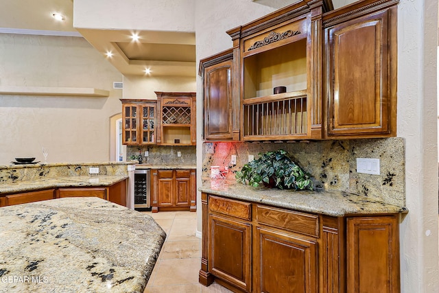 kitchen featuring tasteful backsplash, wine cooler, light stone countertops, and light tile patterned floors