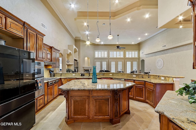 kitchen with kitchen peninsula, ceiling fan, a spacious island, and appliances with stainless steel finishes