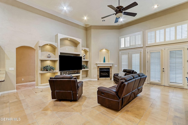 living room with french doors, ceiling fan, a towering ceiling, built in features, and light tile patterned floors