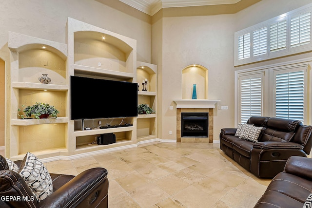 living room with a fireplace, built in shelves, crown molding, and a high ceiling