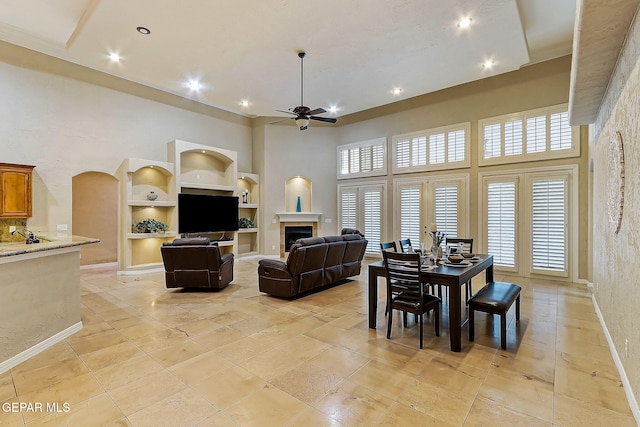 dining area featuring built in shelves, ceiling fan, and a high ceiling