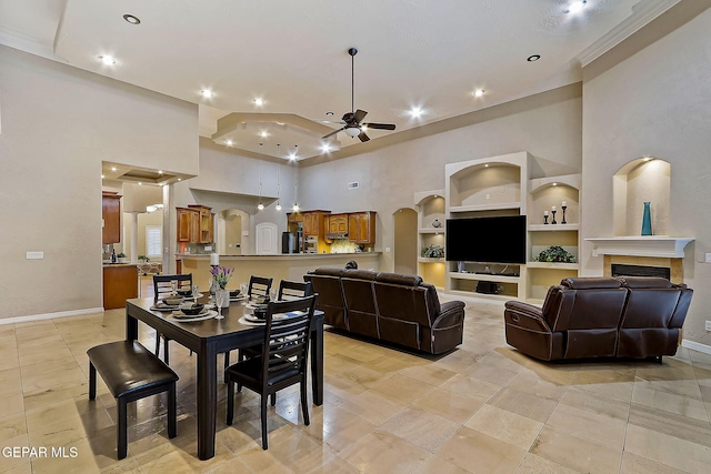 tiled dining space featuring a towering ceiling, built in features, and ceiling fan