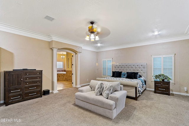 carpeted bedroom with connected bathroom, decorative columns, ceiling fan, and crown molding