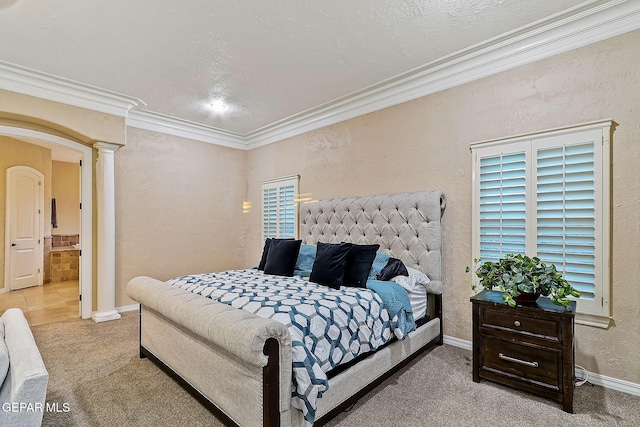 bedroom featuring ensuite bathroom, ornamental molding, light carpet, and decorative columns