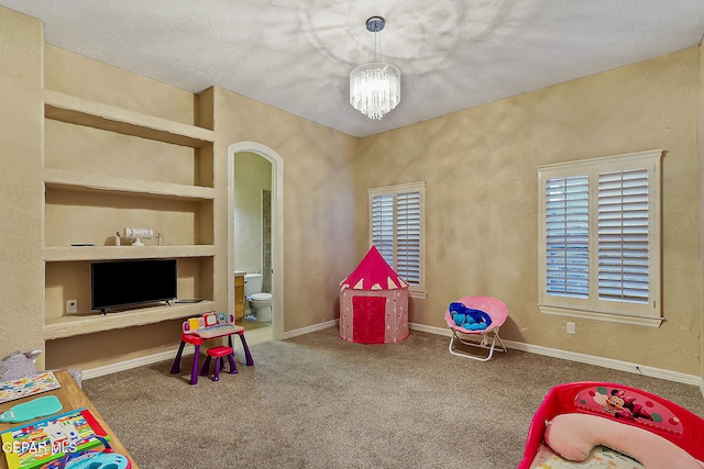 rec room featuring carpet flooring, built in features, a chandelier, and a textured ceiling