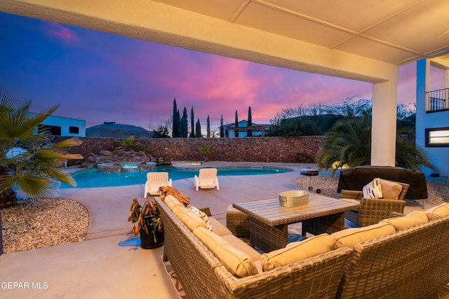 pool at dusk featuring an in ground hot tub and a patio