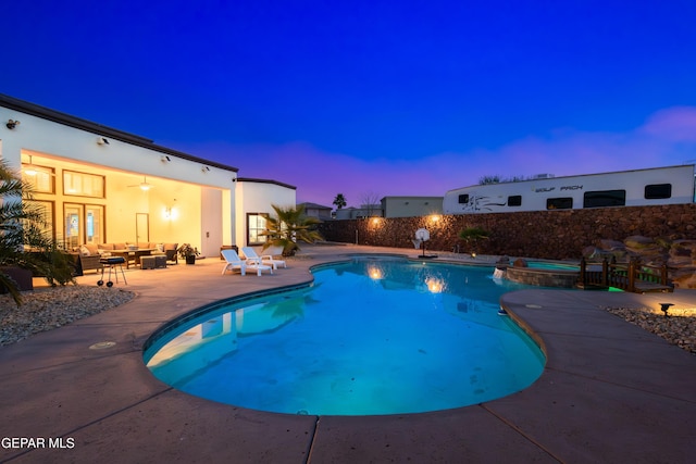 pool at dusk with an in ground hot tub, an outdoor living space, and a patio