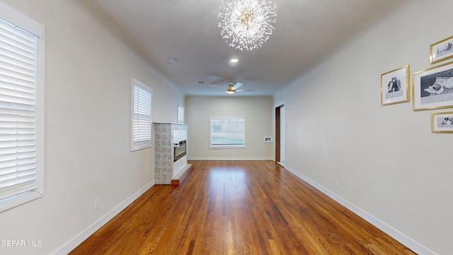 unfurnished living room with ceiling fan with notable chandelier and dark hardwood / wood-style flooring