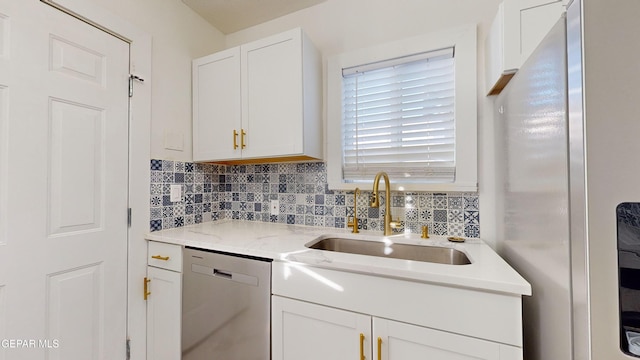 kitchen featuring light stone countertops, backsplash, stainless steel appliances, sink, and white cabinetry