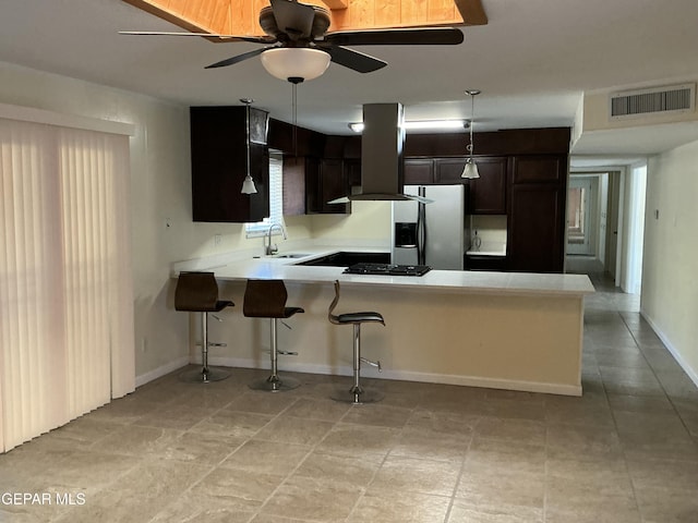 kitchen with a kitchen breakfast bar, sink, stainless steel refrigerator with ice dispenser, ceiling fan, and kitchen peninsula