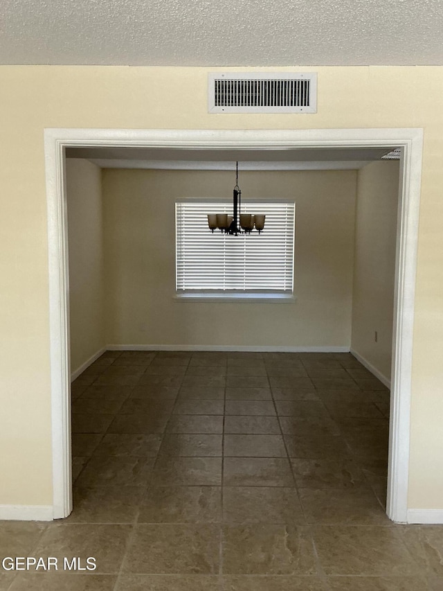 unfurnished dining area featuring a textured ceiling