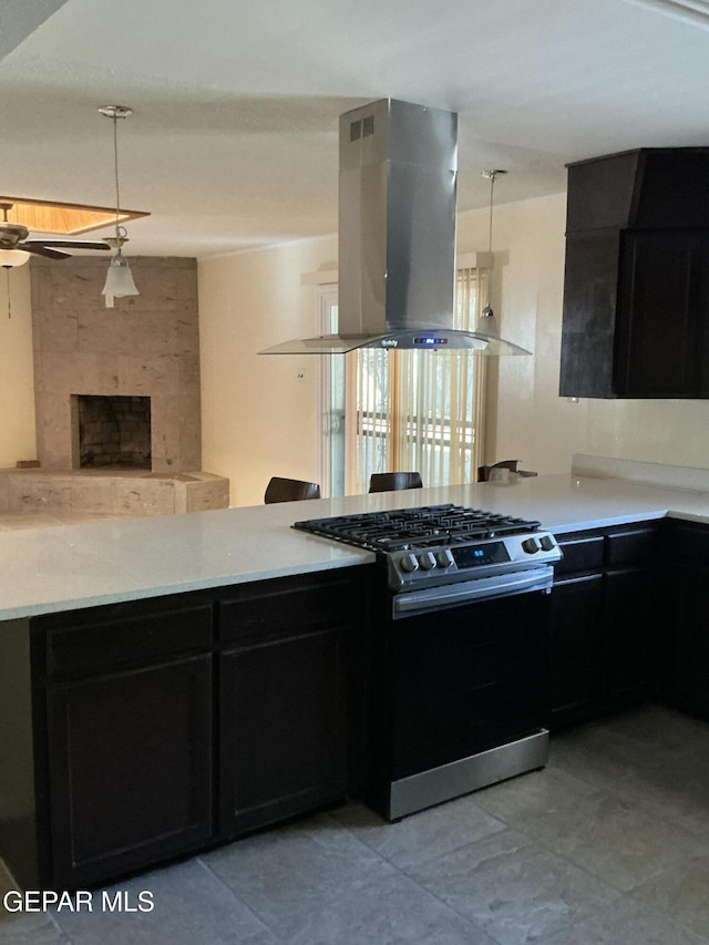 kitchen featuring pendant lighting, a large fireplace, island range hood, and stainless steel gas range