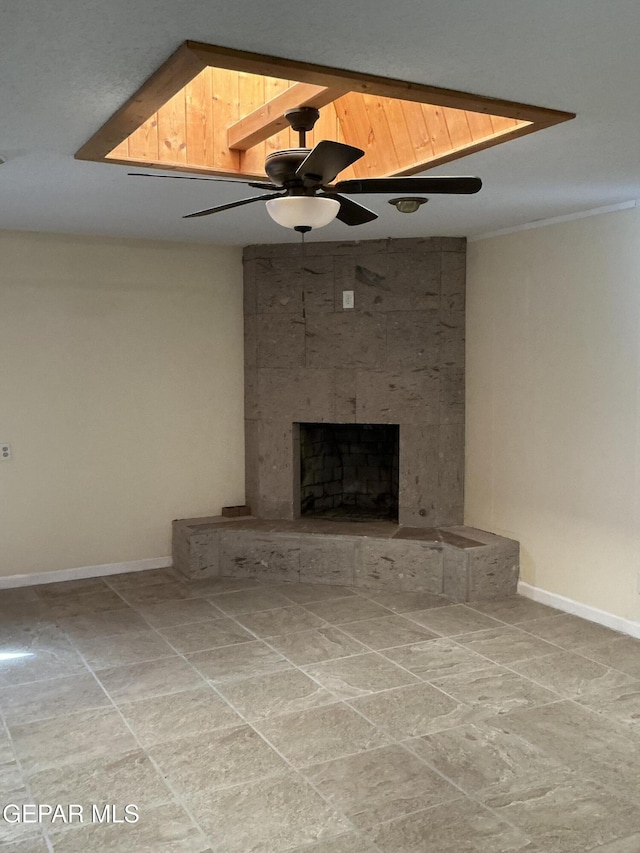 unfurnished living room with a large fireplace and ceiling fan